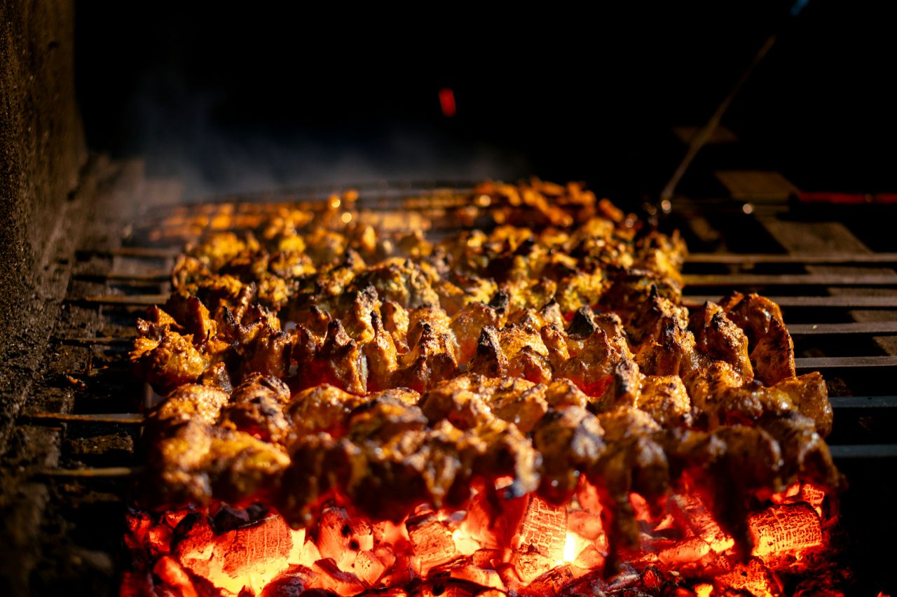 Delicious chicken skewers roasting on open grill with glowing coals and smoky flavor