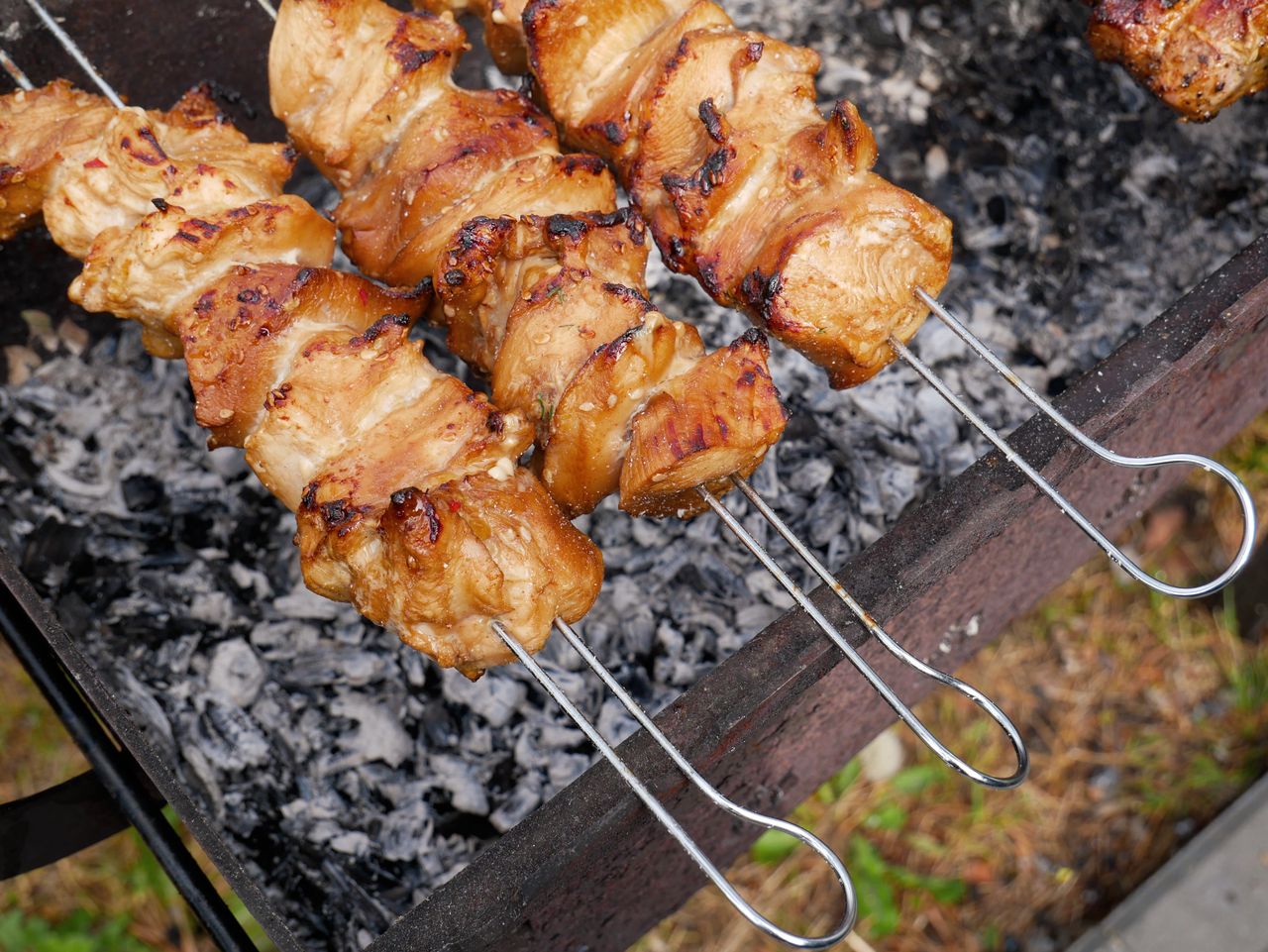 Delicious grilled chicken skewers sizzling over hot charcoal, perfect for outdoor barbecue.
